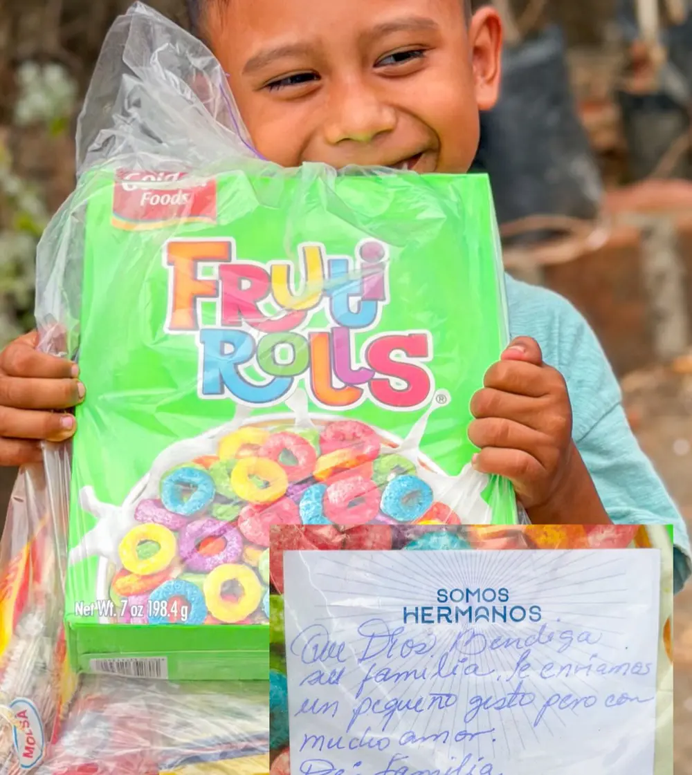 Niño sonriendo con una canasta llena de frutas y golosinas