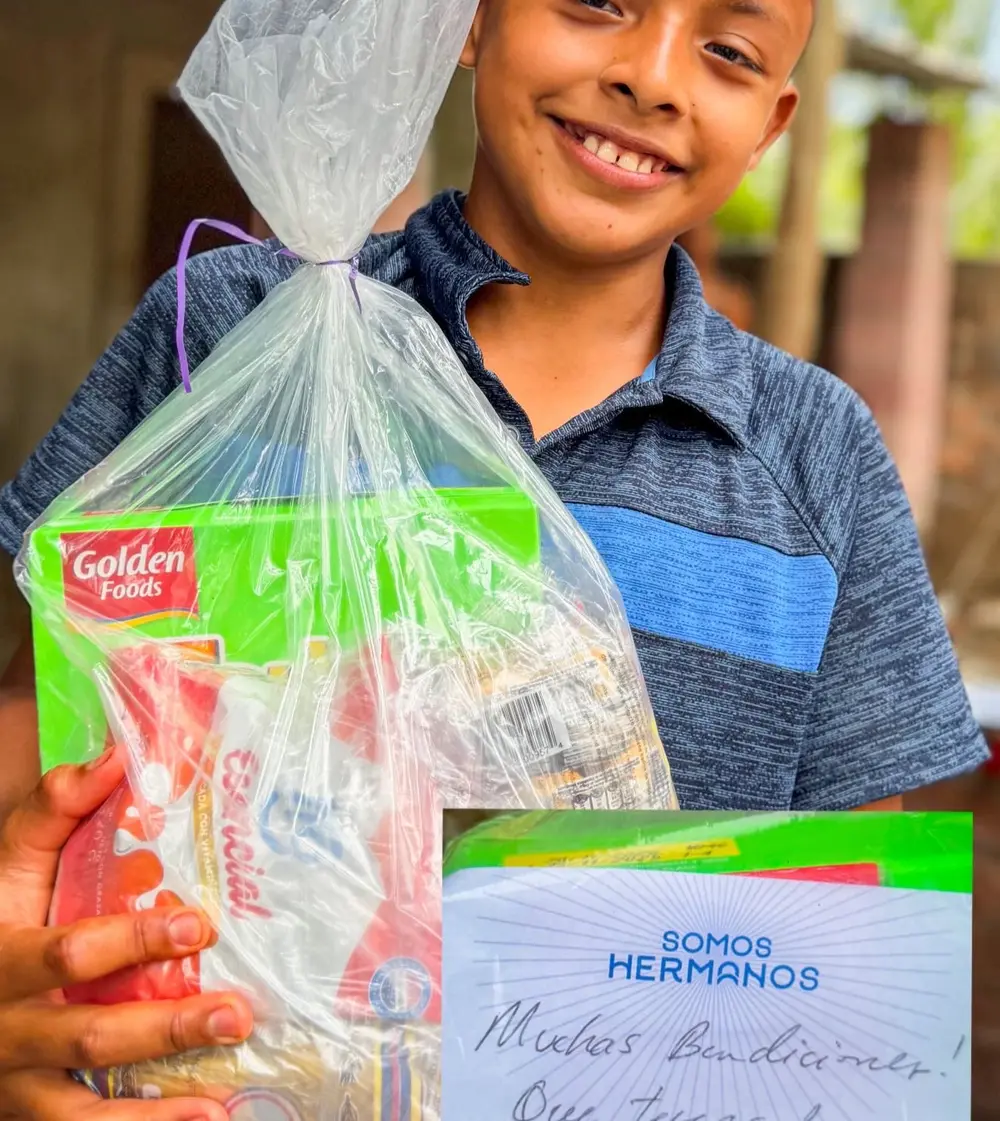 Niño con su canasta de ayuda y una carta con el sello de Somos Hermanos