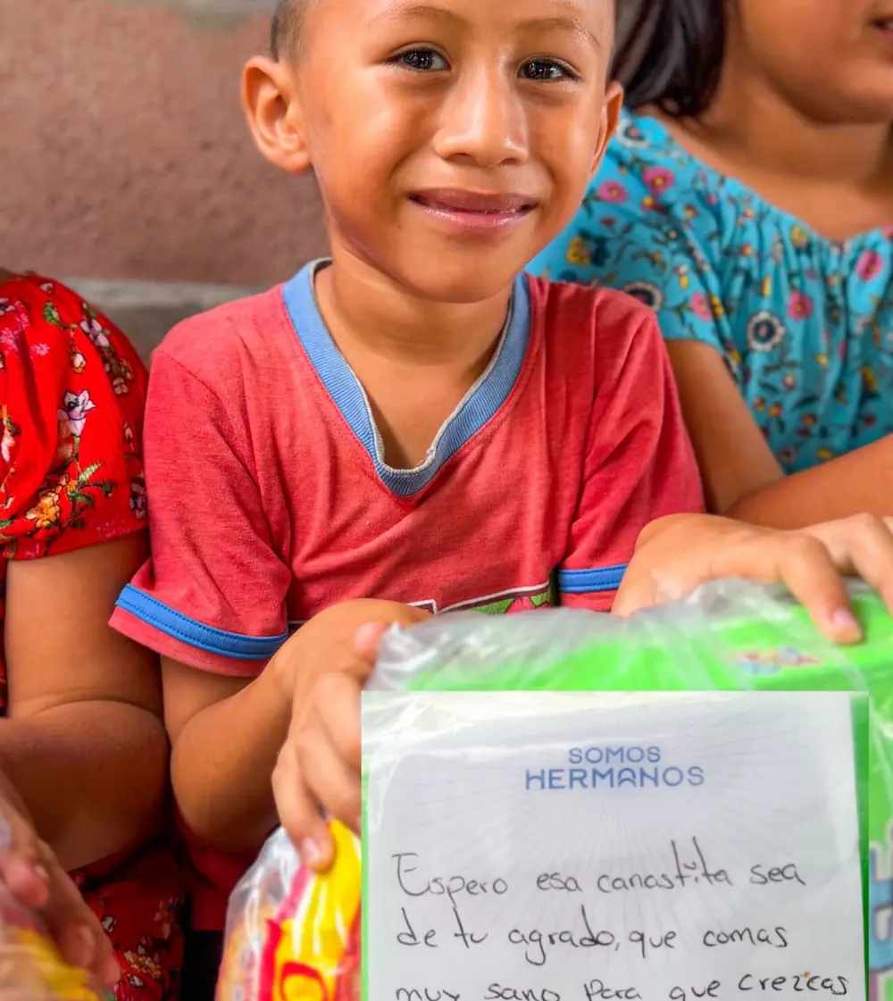 Niño con camiseta roja sosteniendo su canasta y su carta